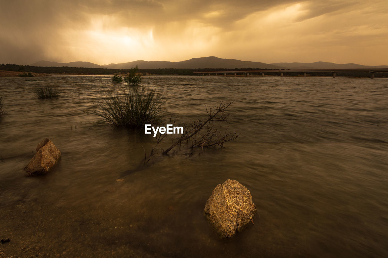 water, sky, reflection, nature, cloud, land, sea, scenics - nature, beauty in nature, morning, environment, shore, landscape, coast, tranquility, beach, sunlight, dawn, sunrise, mountain, ocean, tranquil scene, no people, sand, travel destinations, horizon, outdoors, dramatic sky, travel, seascape, body of water, wave, rock, sun, non-urban scene