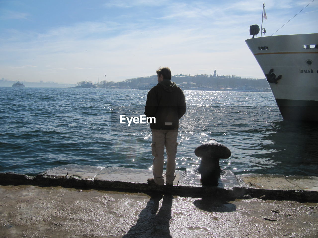 REAR VIEW OF MAN STANDING ON BEACH