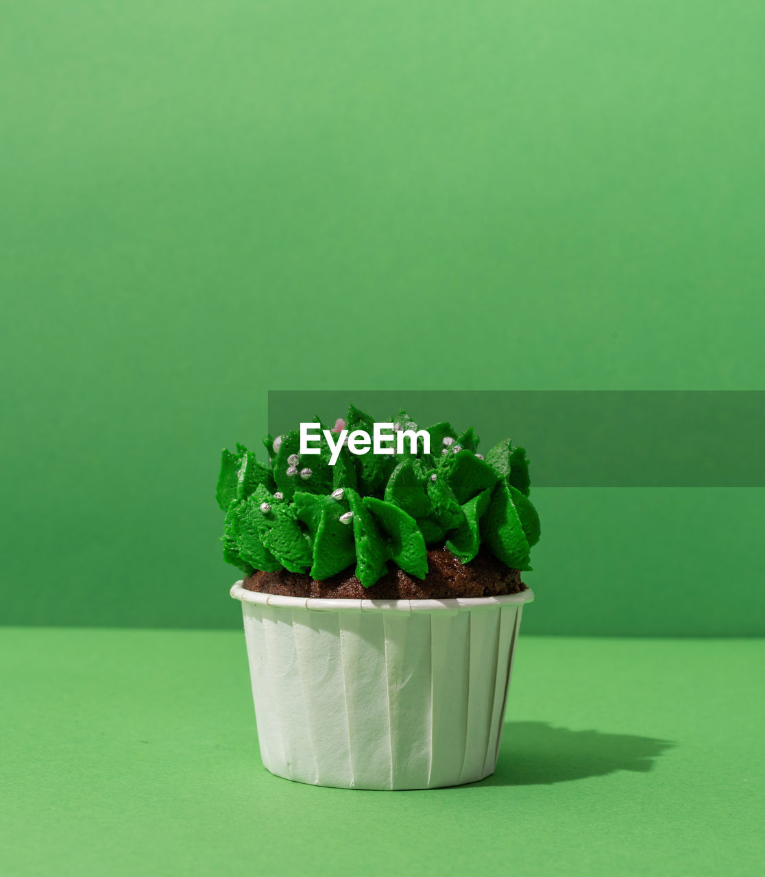 Close-up of cupcakes on table against green background