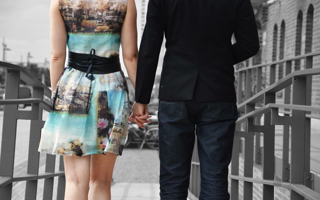 Midsection of couple walking amidst railings in city