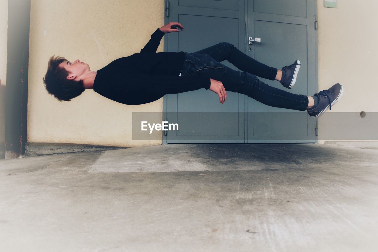 Side view of young man levitating at home