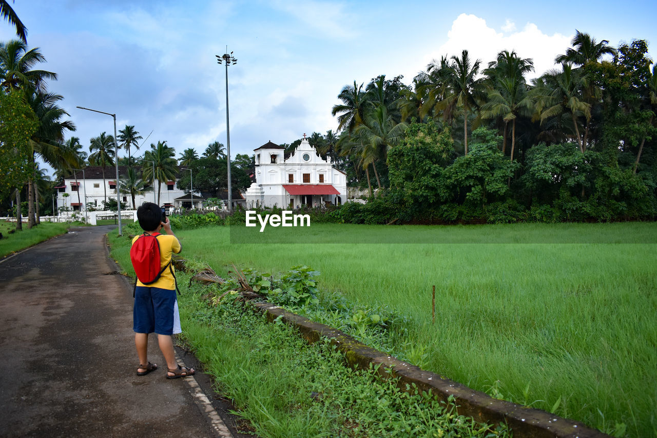 rear view of people walking on field against sky