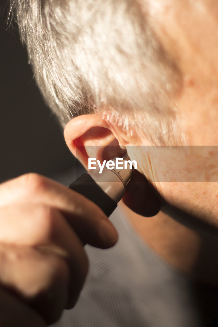 Cropped image of man holding thermometer in ear