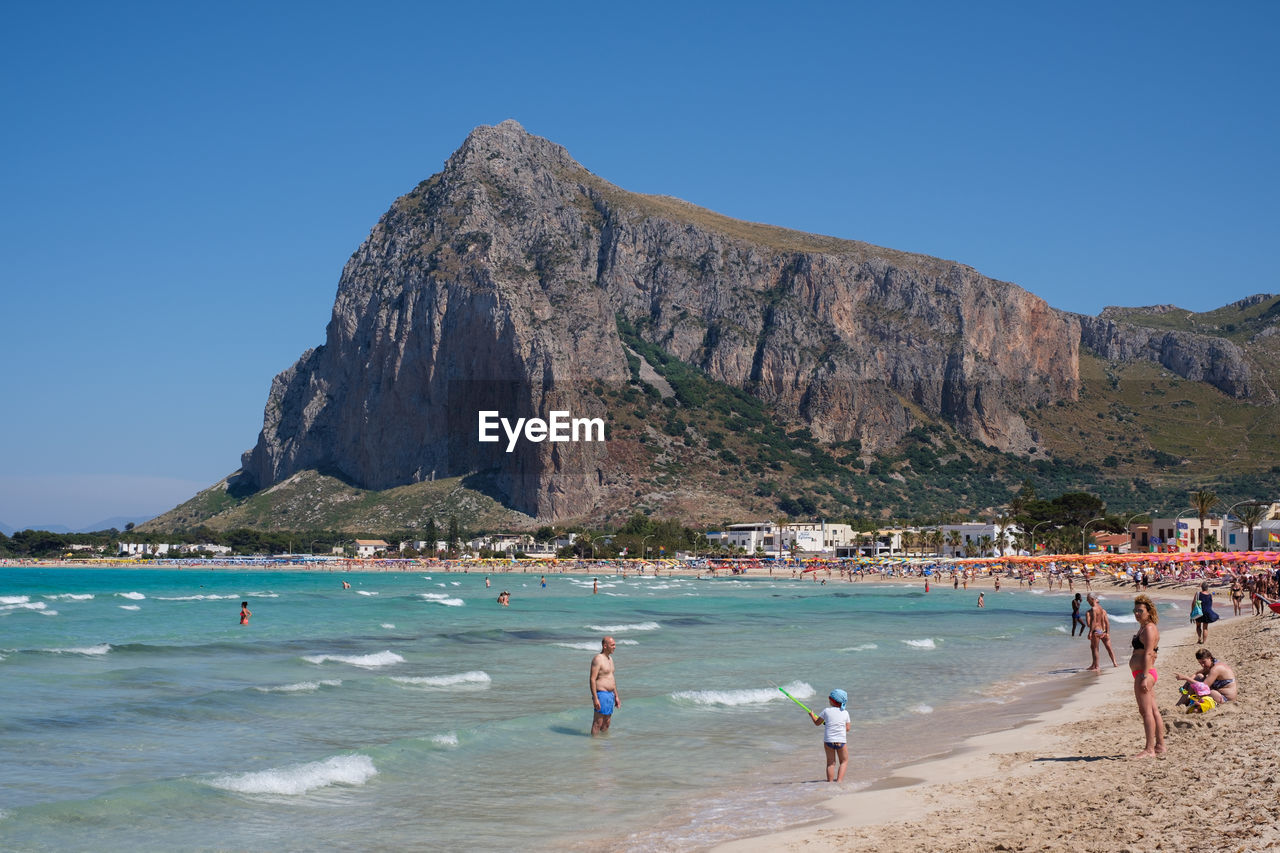 People at beach against mountain 