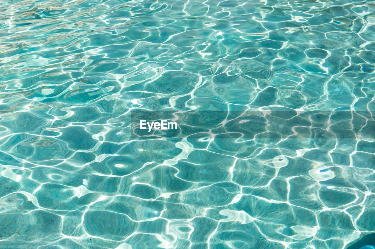 Turquoise blue water in swimming pool, sun reflection, shining water ripple, aqua texture, pattern