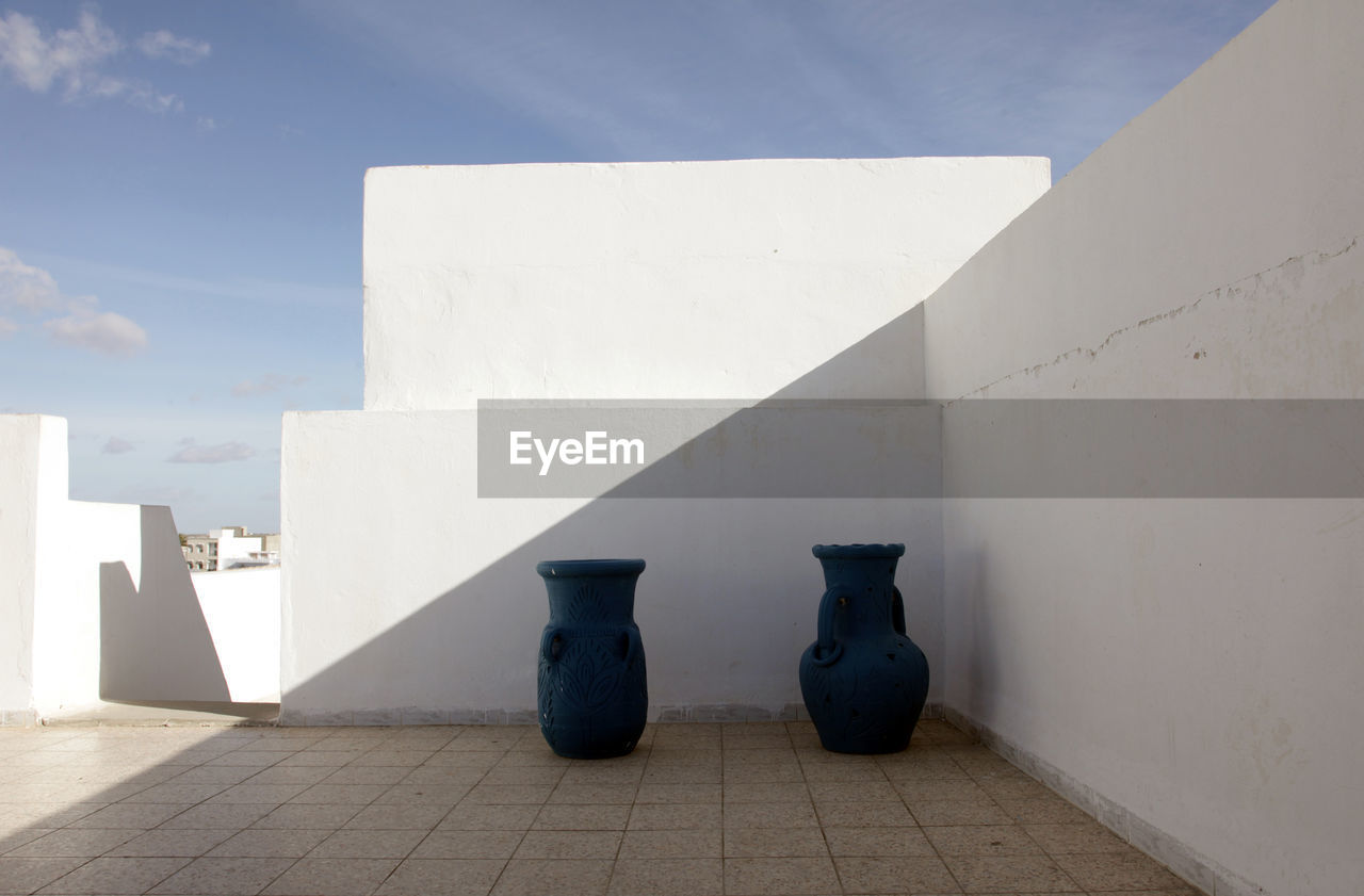 Urns in front of white wall on building terrace