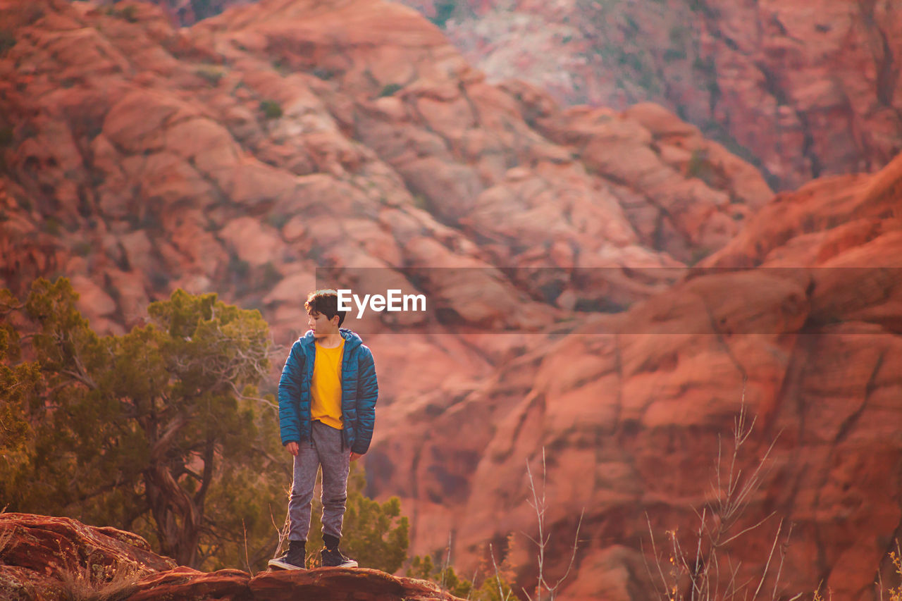 Boy hiking on trail by the red sandstone cliffs and mountains in utah