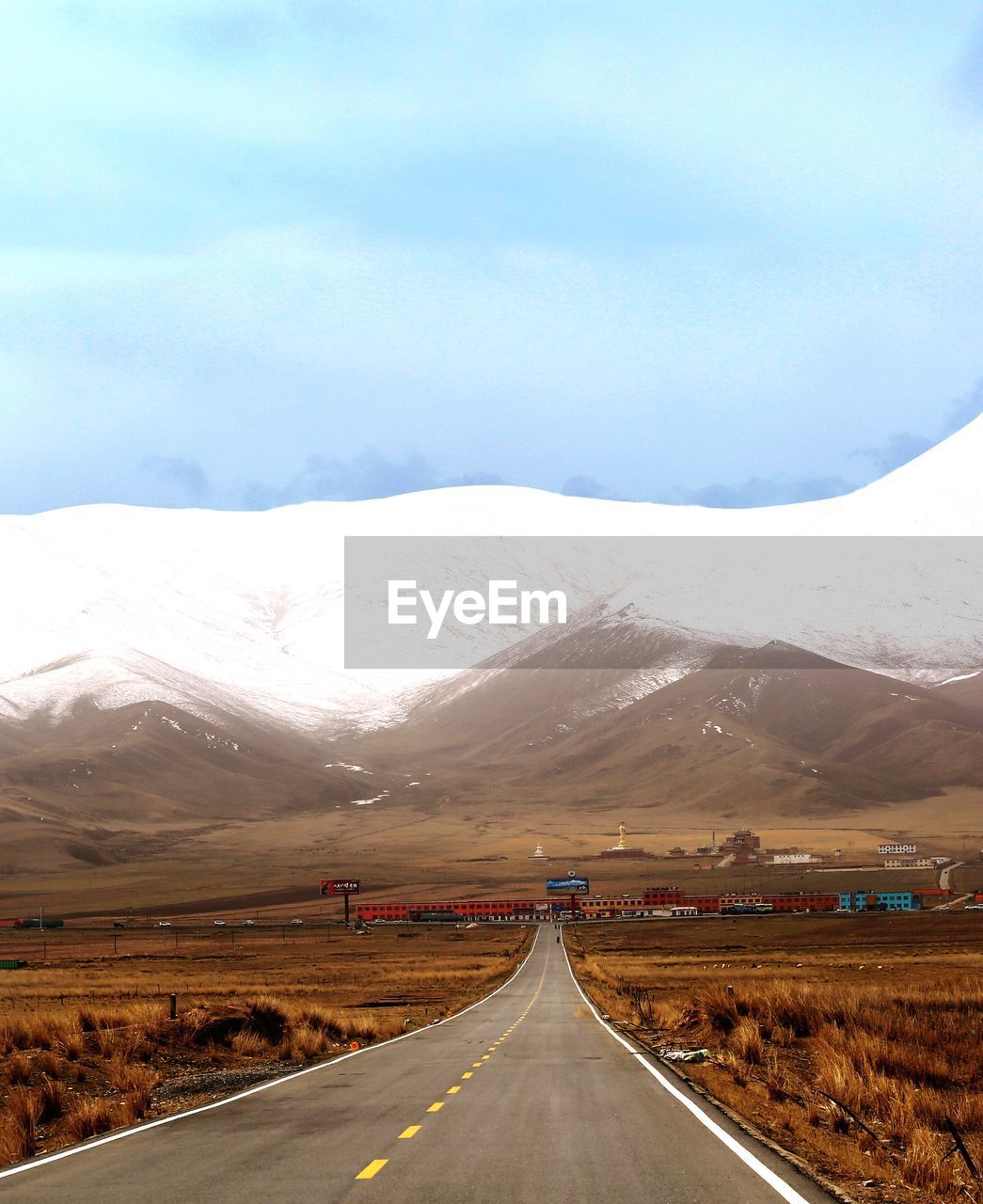 Empty road leading towards mountains against sky