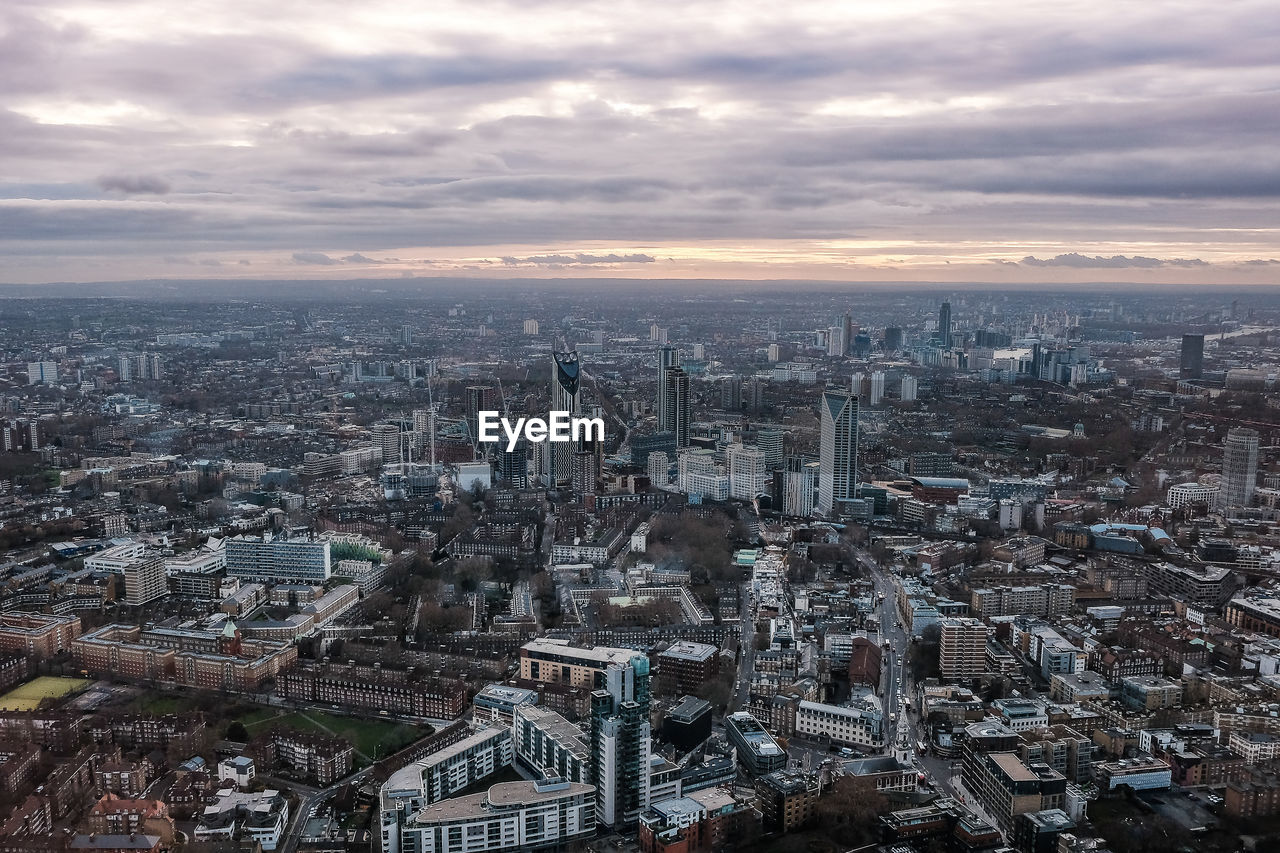 High angle view of city buildings against cloudy sky