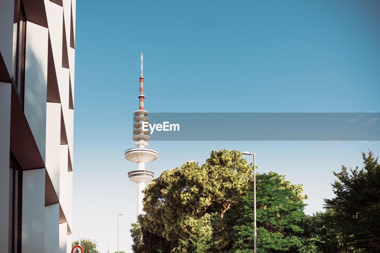 Low angle view of communications tower against blue sky during sunny day