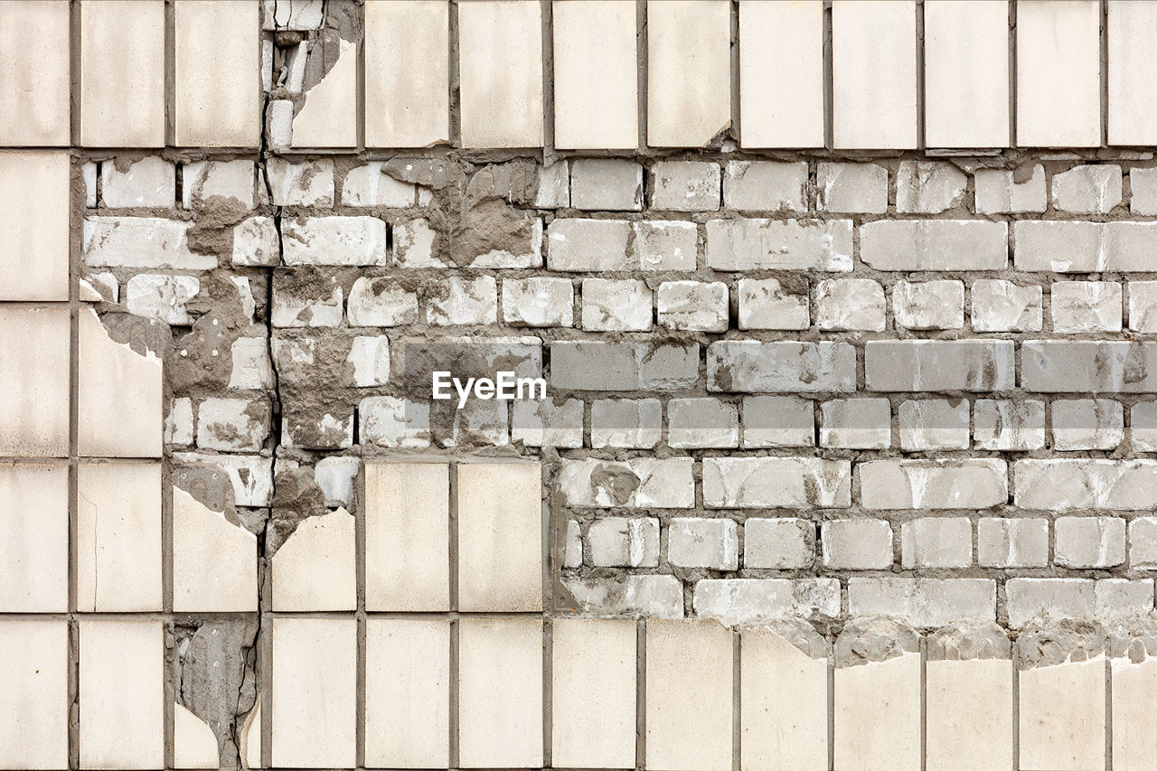 A fragment of the destruction of the facade of a wall with a fallen off rectangular facade tile.