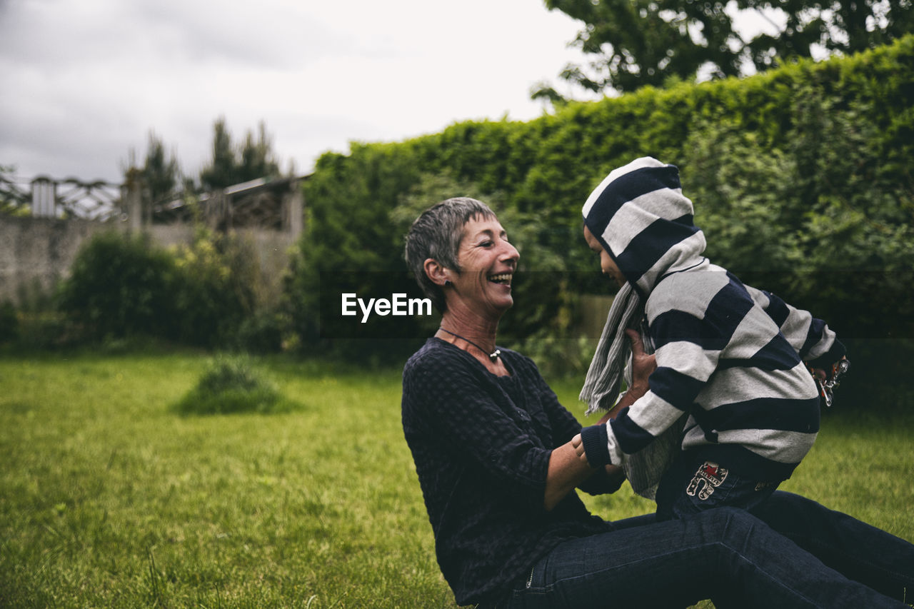 Happy grandmother with grandson on grassy field