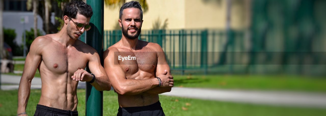 Panoramic view of shirtless muscular men standing in park