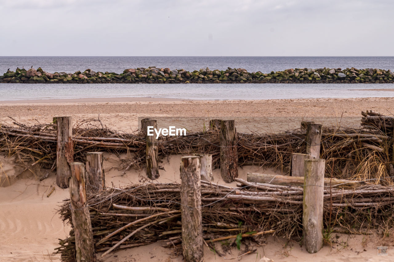 WOODEN POSTS ON BEACH