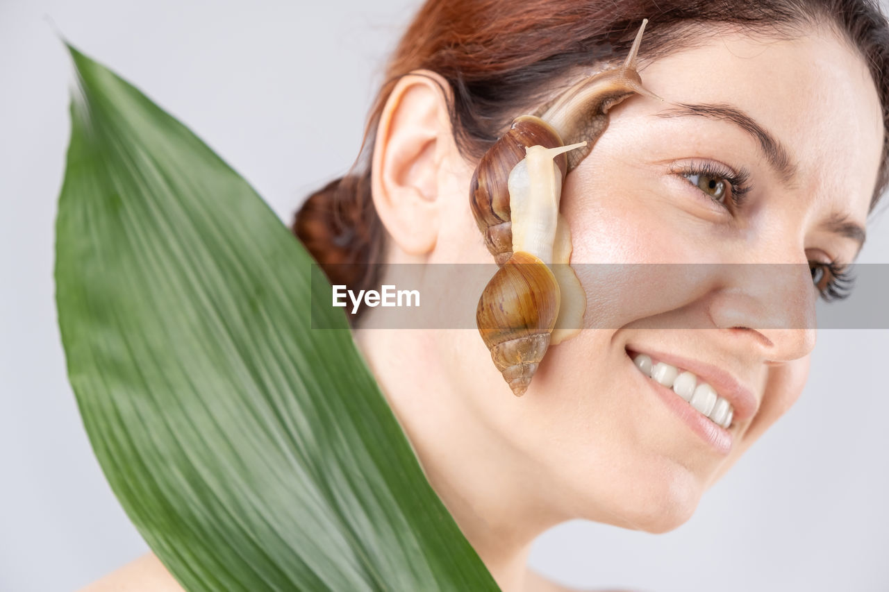 Close-up of smiling young woman with snail of face