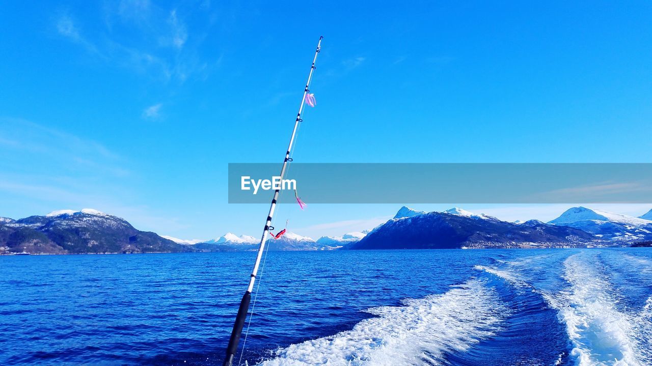 Fishing rod on sea against blue sky