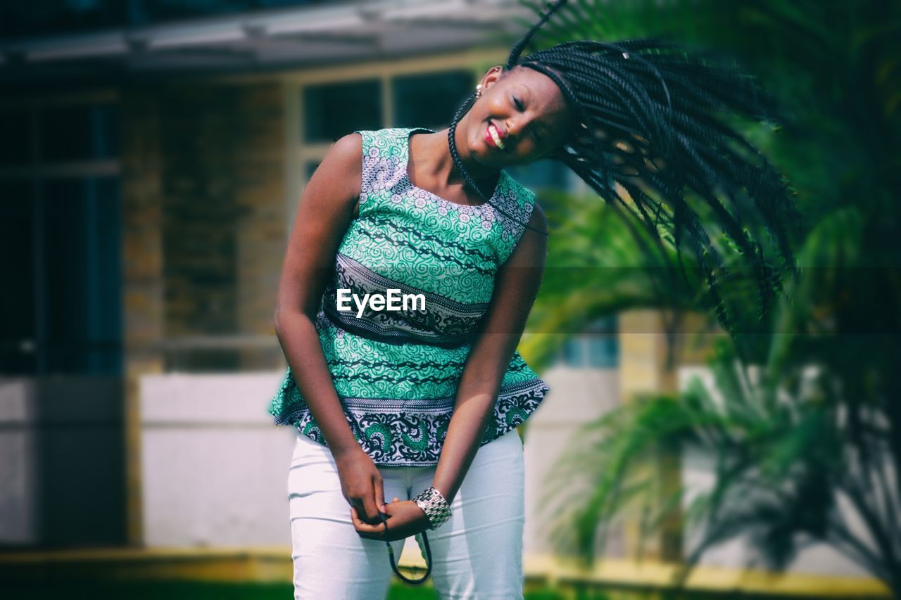 Happy young woman shaking head while standing at yard