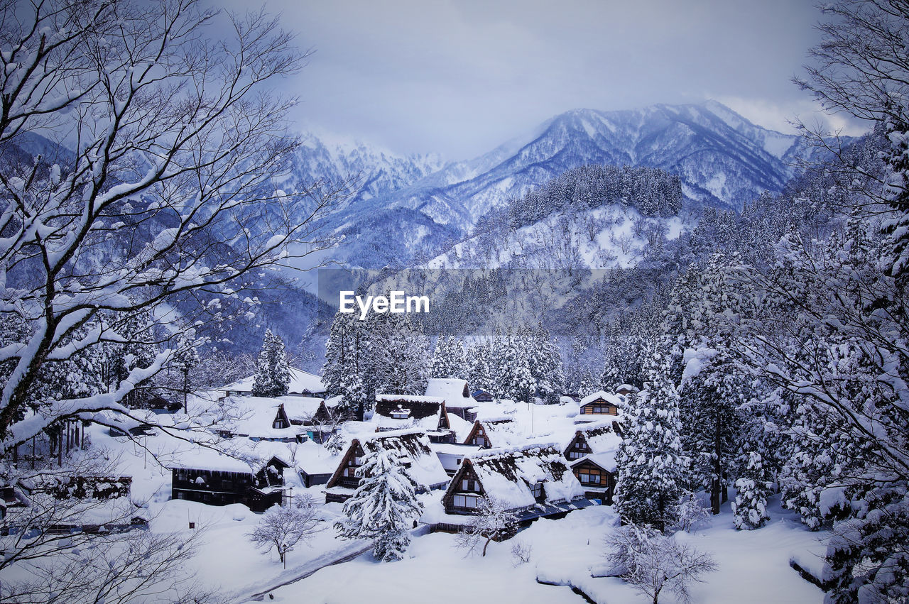 High angle view of snow covered houses and trees by mountains