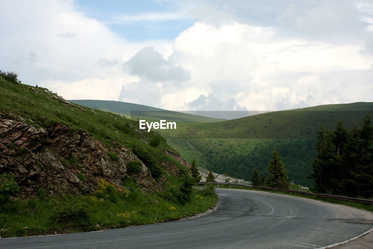 Scenic view of road by mountains against sky