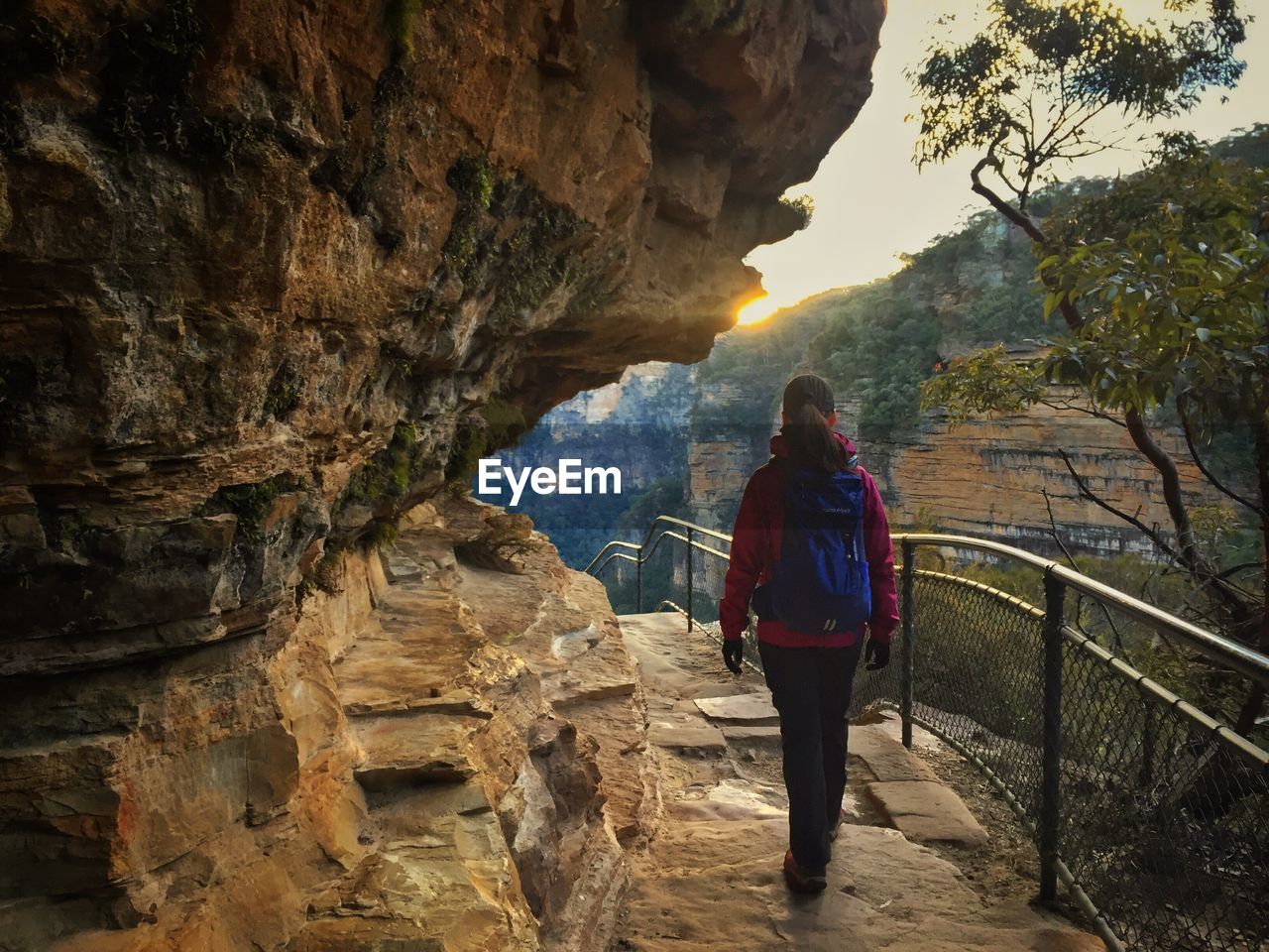 REAR VIEW OF WOMAN STANDING ON CLIFF AGAINST MOUNTAINS