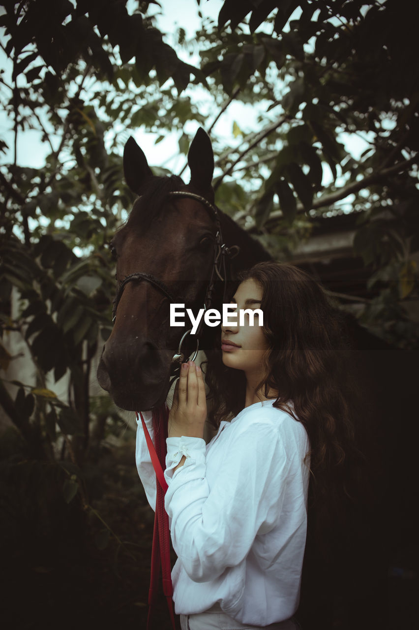 rear view of young woman riding horse on field against sky