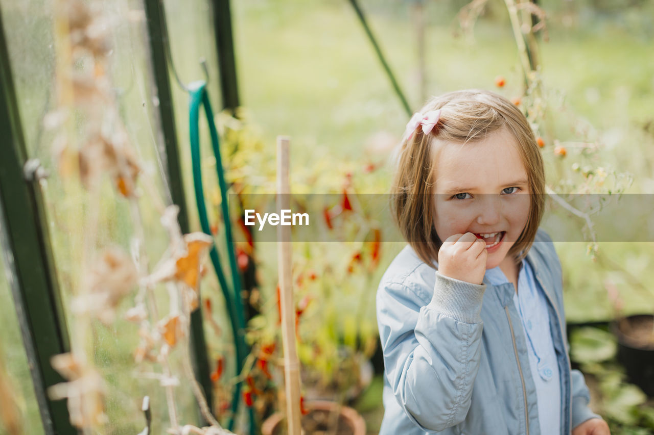 Girl in greenhouse eating tomato