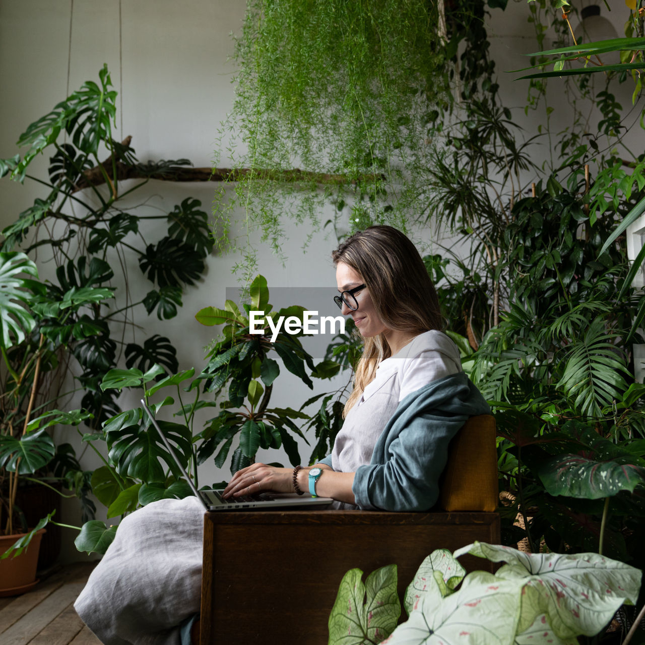 Woman sitting on chair by plants