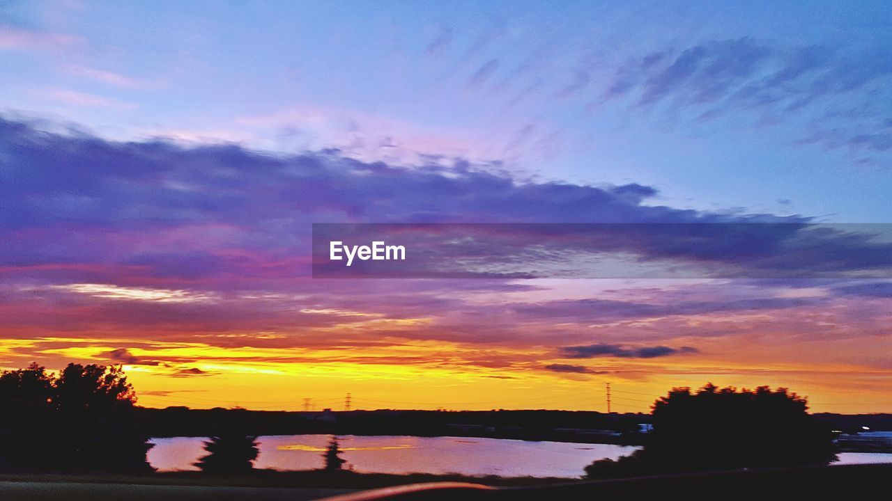 SCENIC VIEW OF RIVER AGAINST SKY AT SUNSET