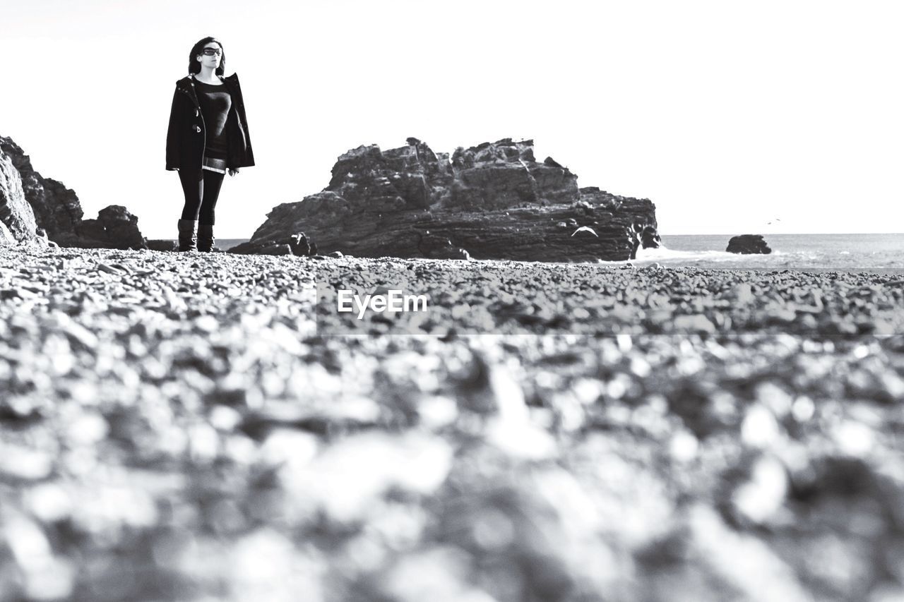 Woman standing at seaside against clear sky