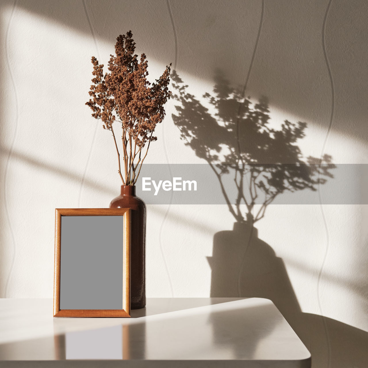  wooden brown frame mock up, clay vase with brown dried flowers on a white coffee table 