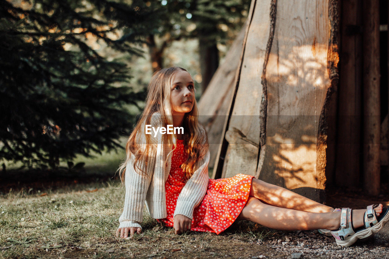 side view of young woman standing against trees