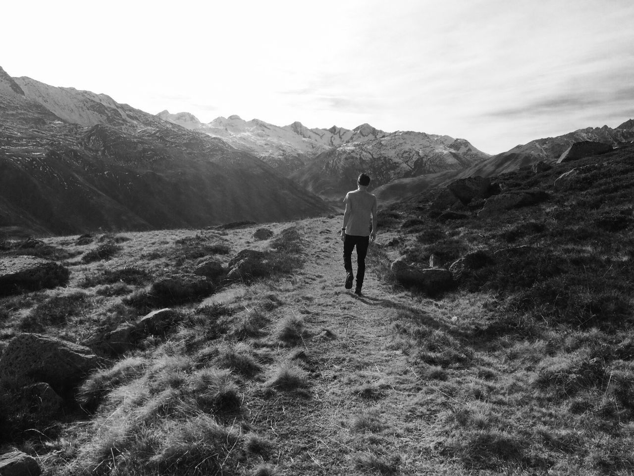 Full length rear view of man walking by mountains against sky