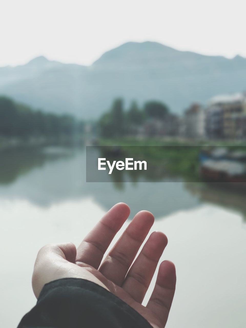 Cropped image of man hand against lake 