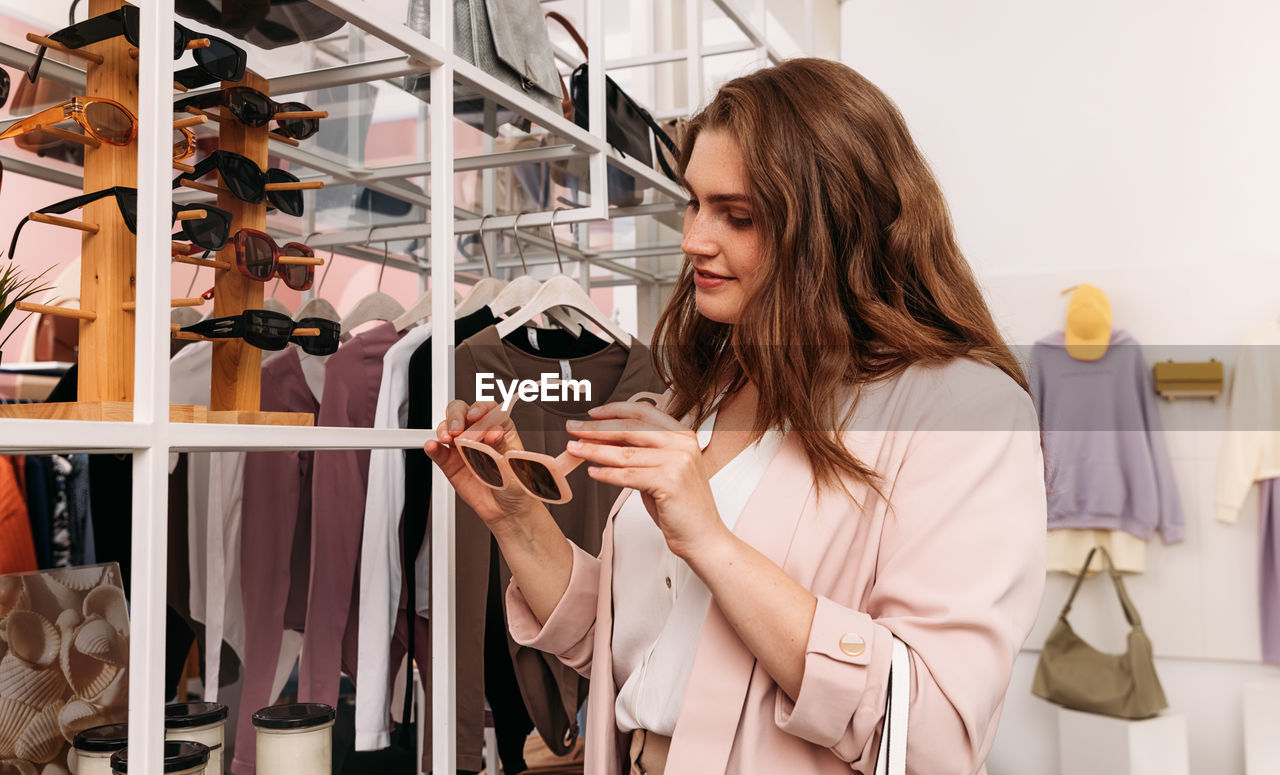 Young woman holding sunglasses at store