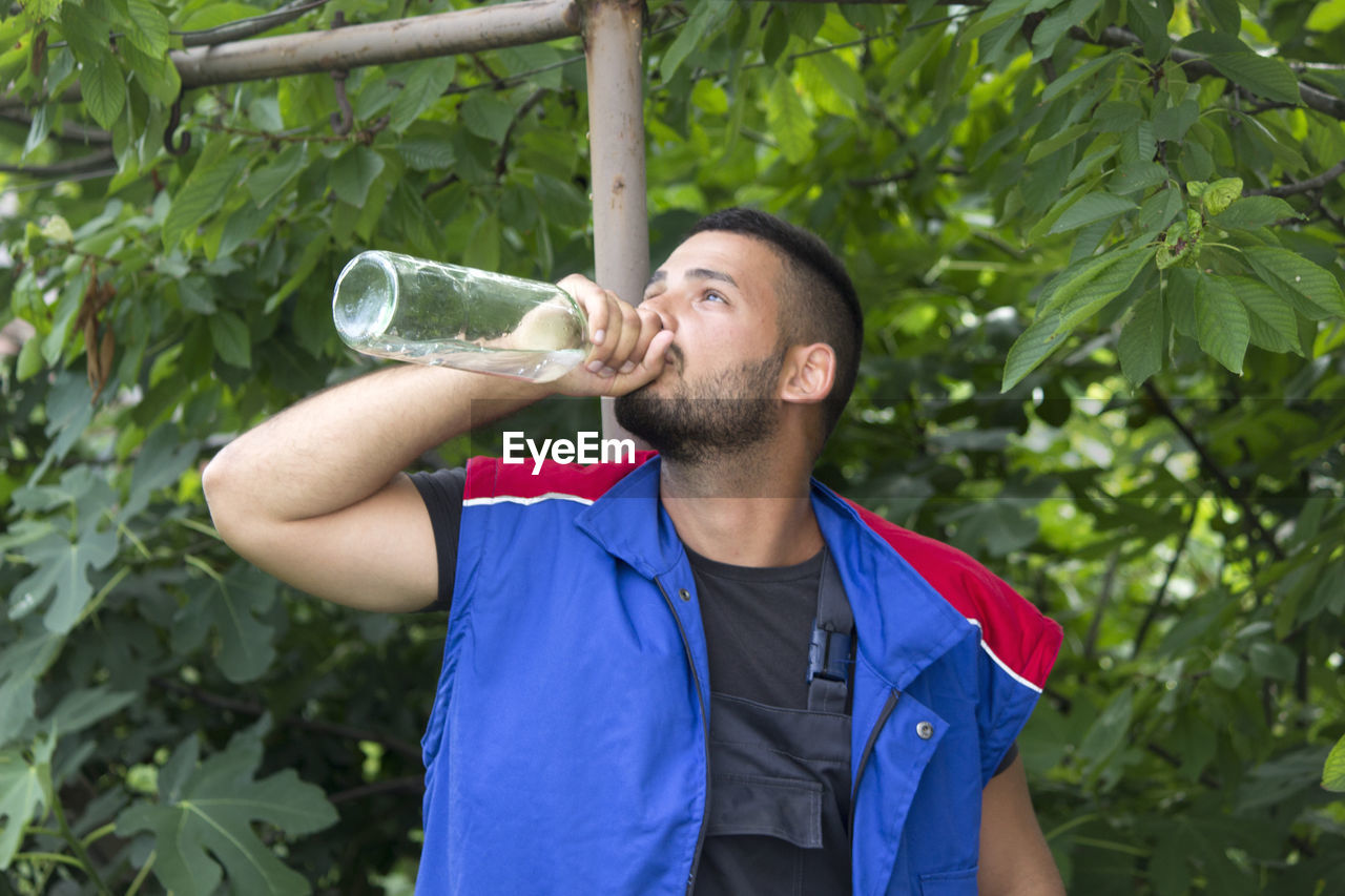 MID ADULT MAN DRINKING GLASS WITH DRINK IN BACKGROUND