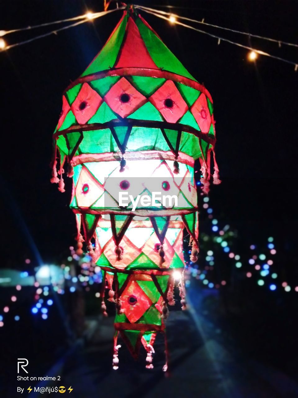 LOW ANGLE VIEW OF ILLUMINATED LANTERNS HANGING AT NIGHT