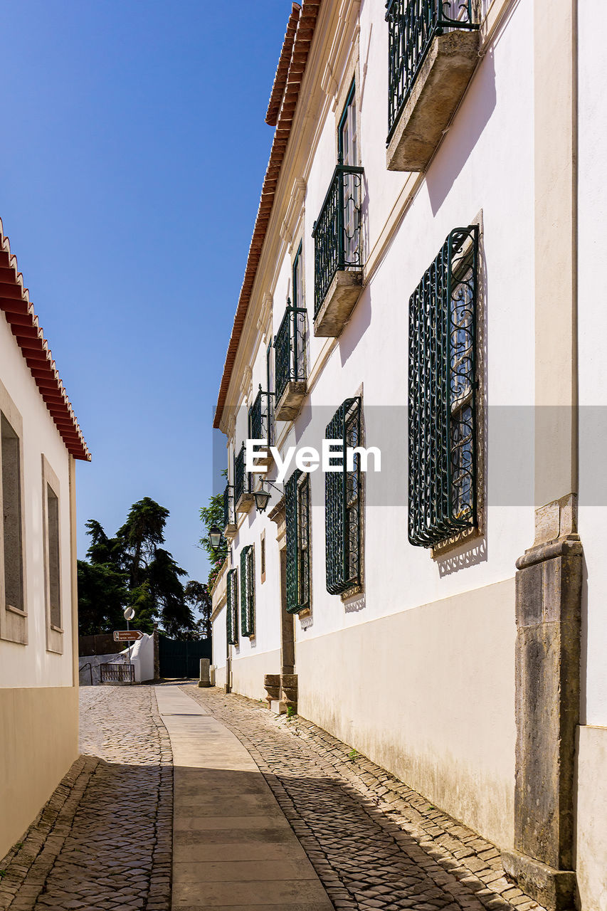 Street of a portuguese town with low rise white buildings and paving stones on the road