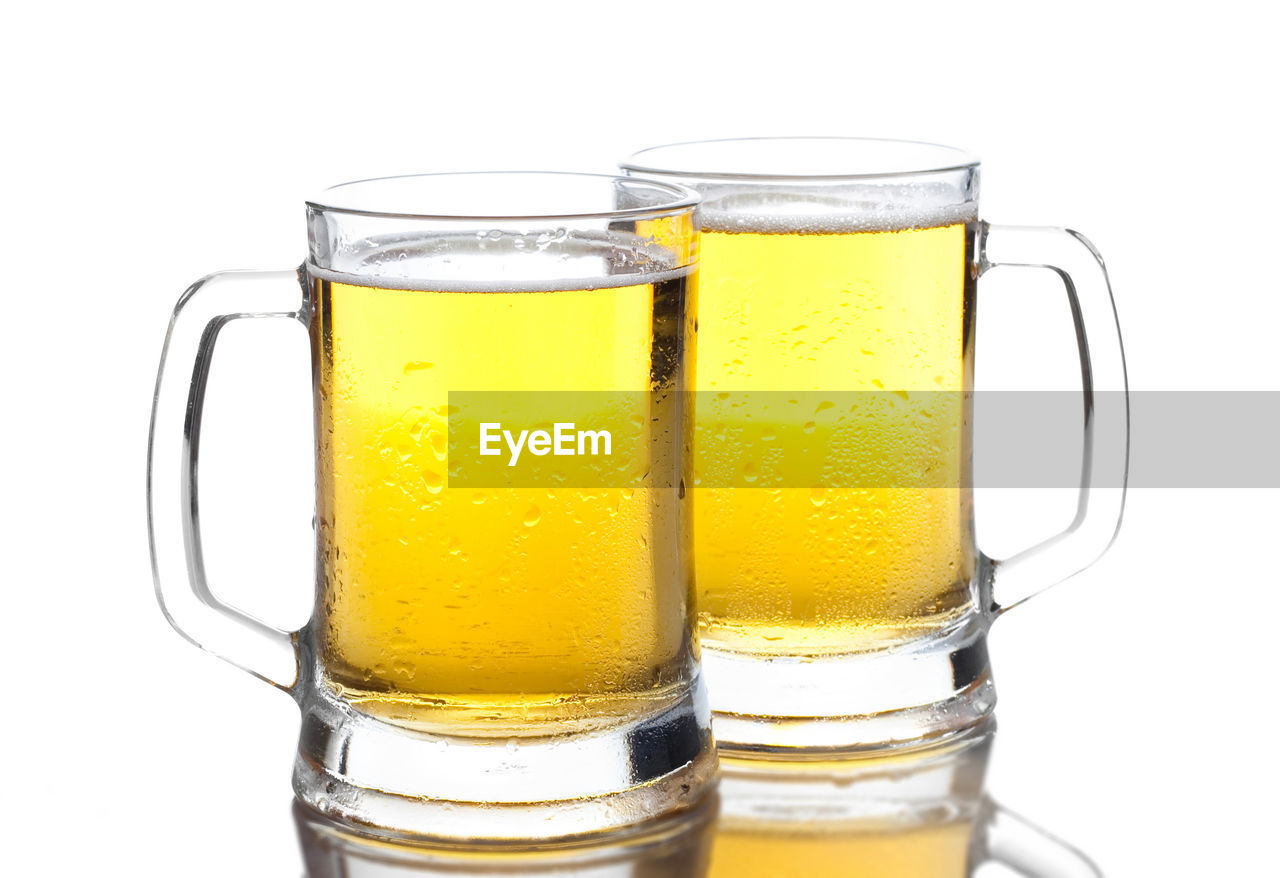 Close-up of beer in glasses against white background
