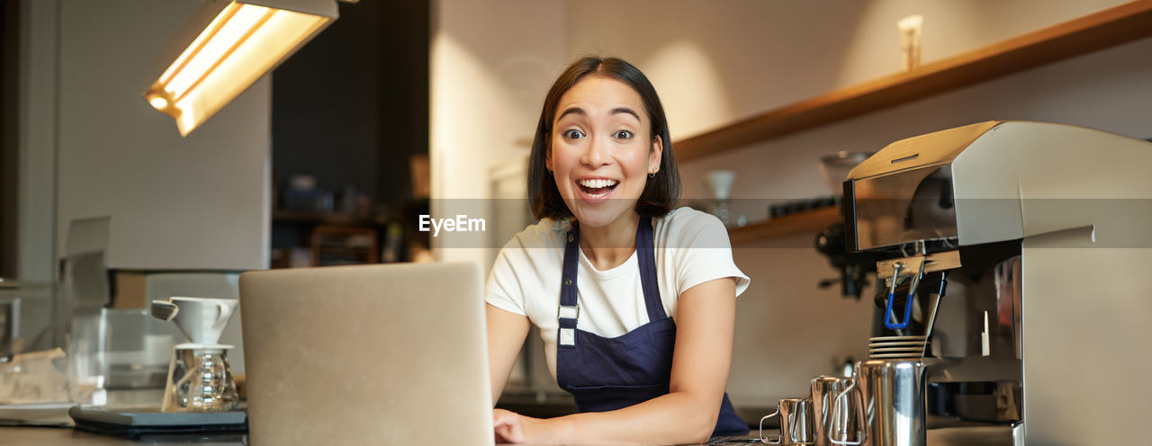 portrait of young woman using mobile phone while sitting at home