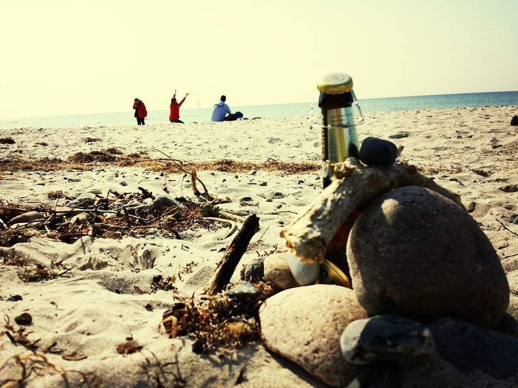 Abandoned bottle by rock on sand at beach