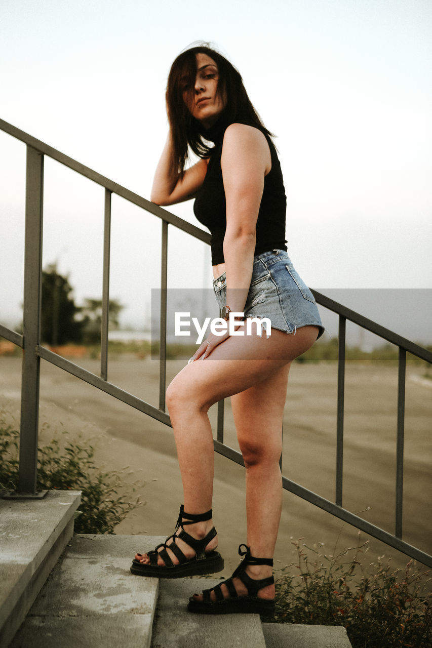 Full length of woman standing on steps against sky