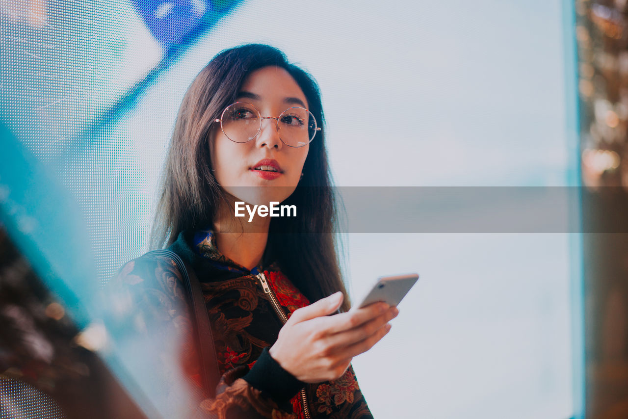 YOUNG WOMAN USING MOBILE PHONE