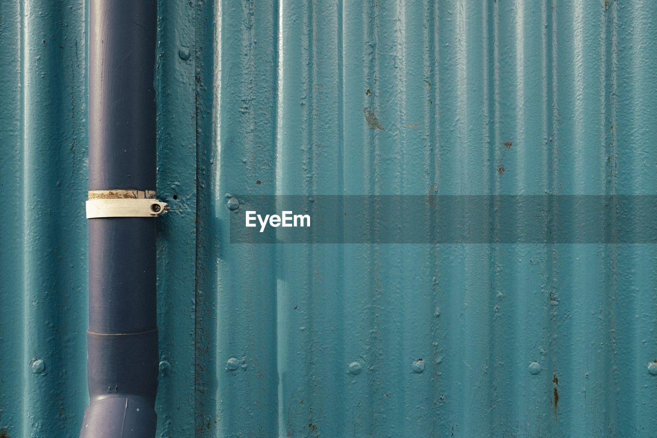 Pipe on corrugated iron fence