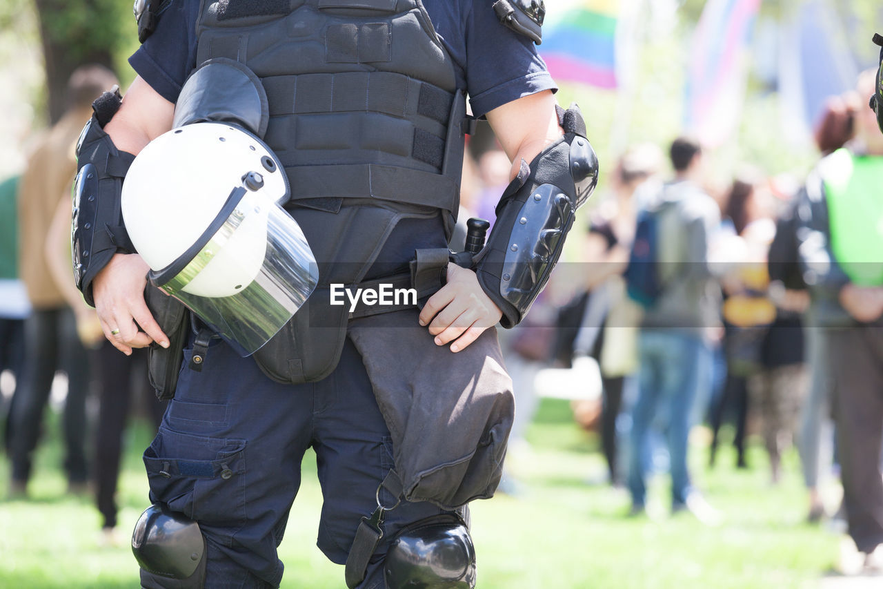 Midsection of police force against crowd during protest