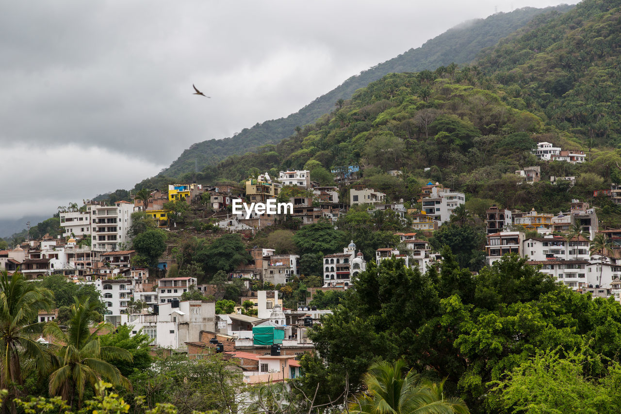 Buildings by mountain against sky