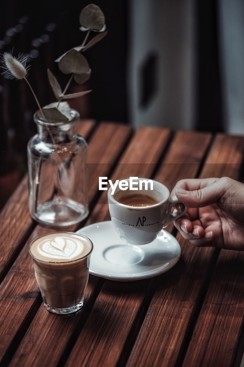 CLOSE-UP OF COFFEE CUP AND WINE ON TABLE