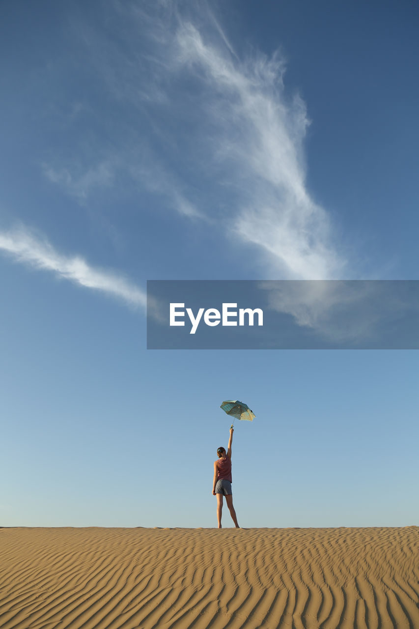 Full length of woman standing on desert against sky