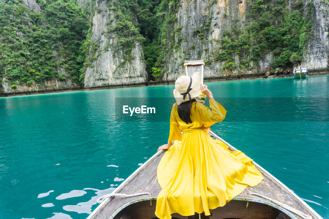 REAR VIEW OF YELLOW UMBRELLA ON SEA