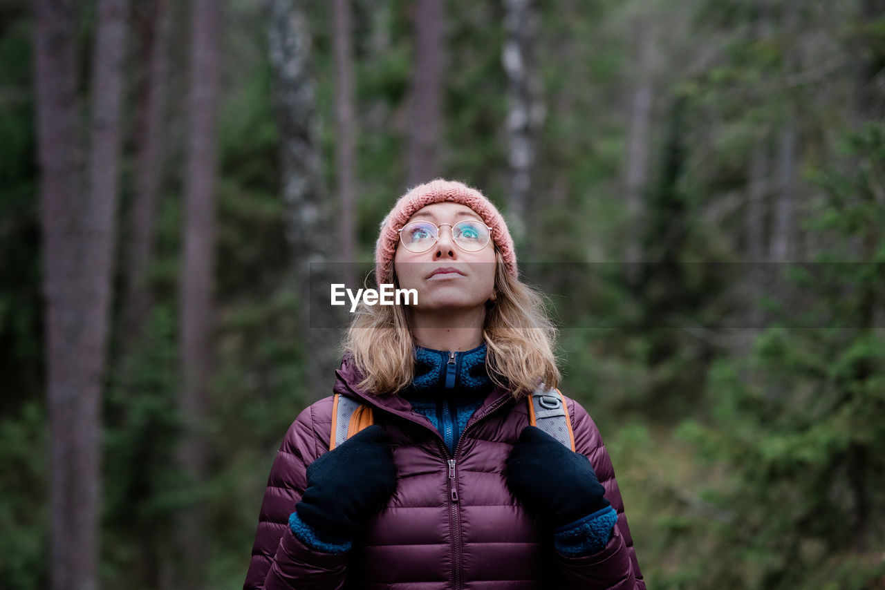 Portrait of a woman looking up at the sky in a forest in winter