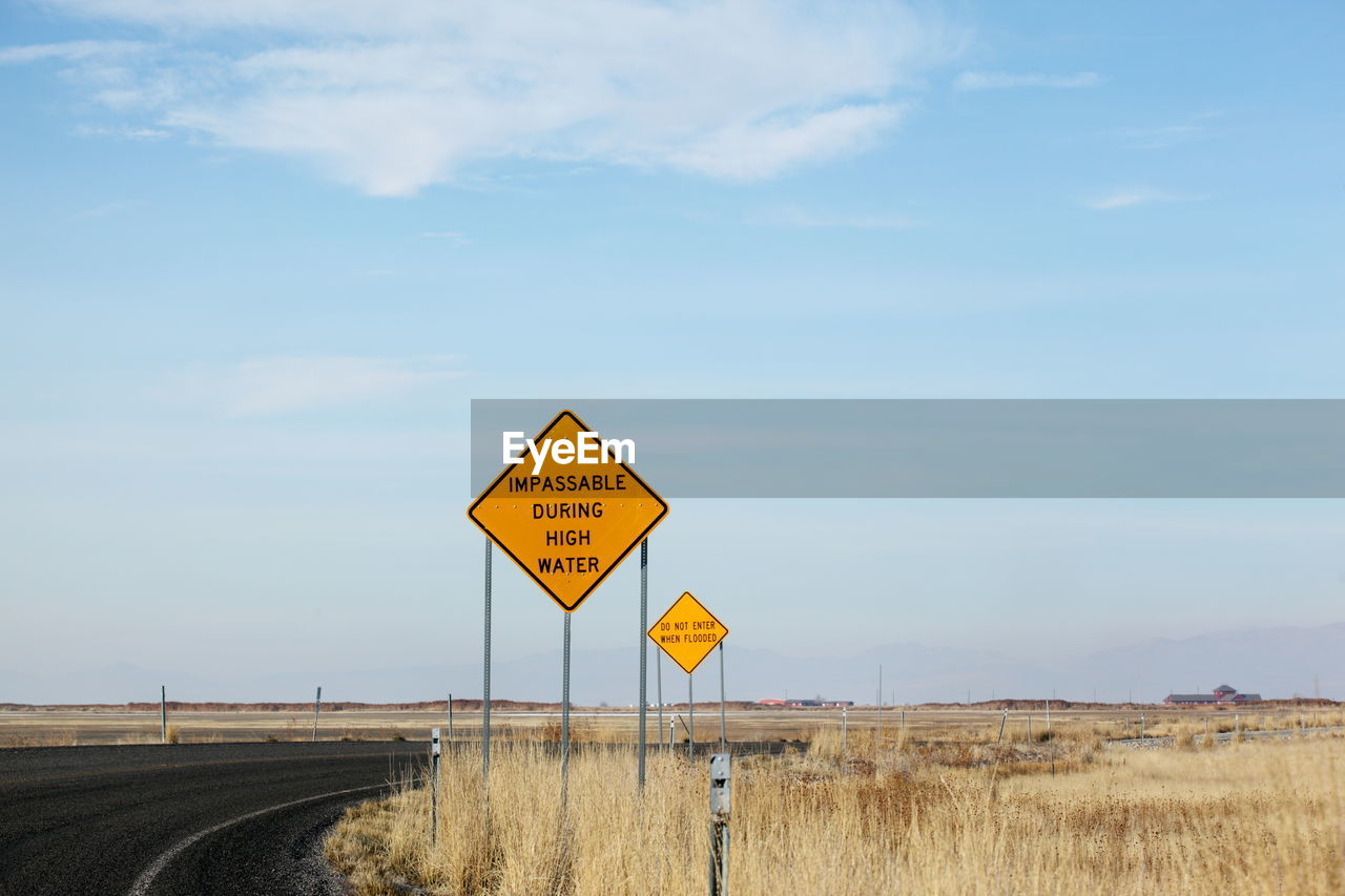 Information sign on road against sky